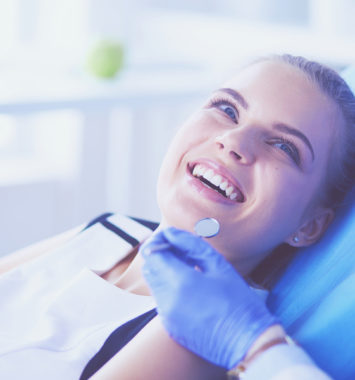 Young Female patient with pretty smile examining dental inspection at dentist office.